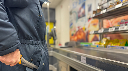 Person, die mit einem Messer in der Hand an der Kasse im Supermarkt steht