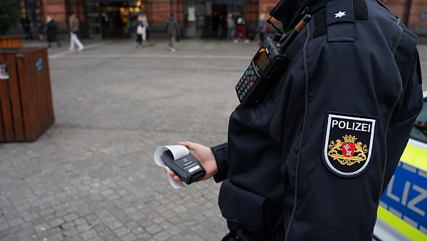 Auf dem Bild ist ein Polizist zu sehen, der vor dem Hauptbahnhof eine Kontrollquittung ausstellt.