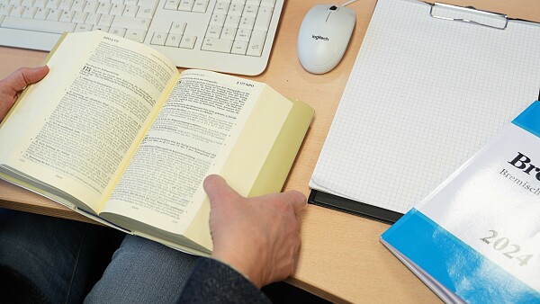 Auf dem Foto ist ein Gesetzesbuch, ein Block, sowie ein weiteres Buch zu sehen