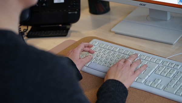 Auf dem Foto ist eine Frau zu sehen, die etwas auf einer Tastatur tippt